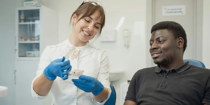 A dentist explaining to a patient using a dental cast.
