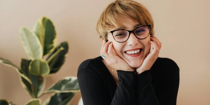 A woman smiling while looking at a camera.