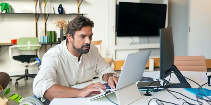 A bearded man typing on his laptop.