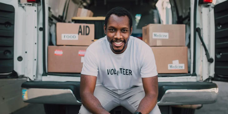 A volunteer sitting in the back of an open van, preparing to deliver donated goods.