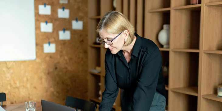 A woman standing while working on her laptop.