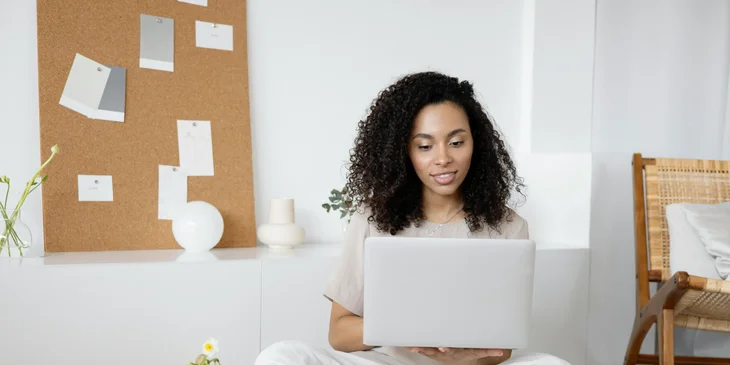 A woman sitting and holding a laptop.