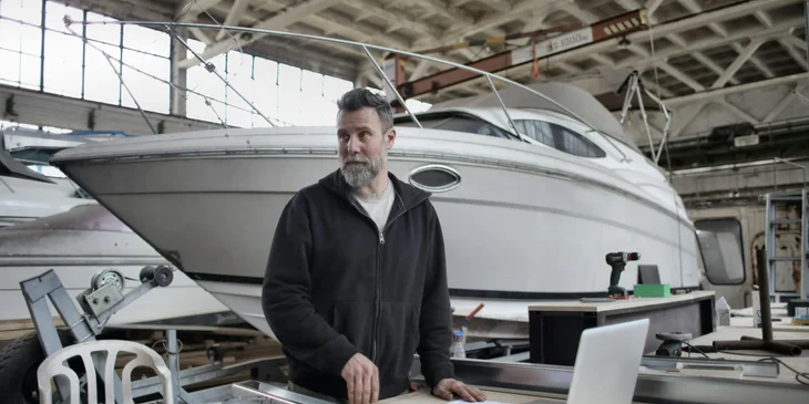 A man working in a boat repair workshop.
