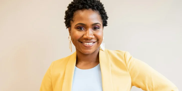 A woman in yellow blazer smiling.