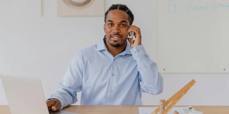 A man using a laptop while talking on the phone.