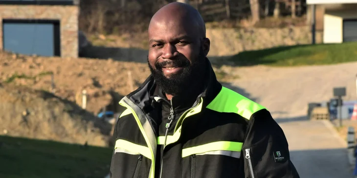 A man wearing a black jacket smiling.
