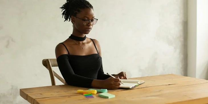 A focused woman writing notes in a notebook.