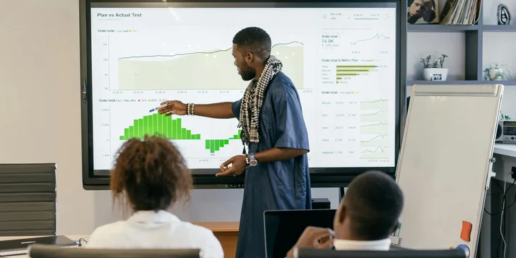 A man presenting data on a large monitor.