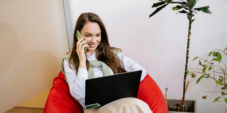 A woman sitting on a bean bag while working.