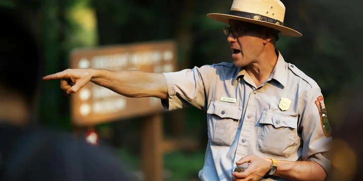 A park ranger pointing to an area that is prohibited for exploration.