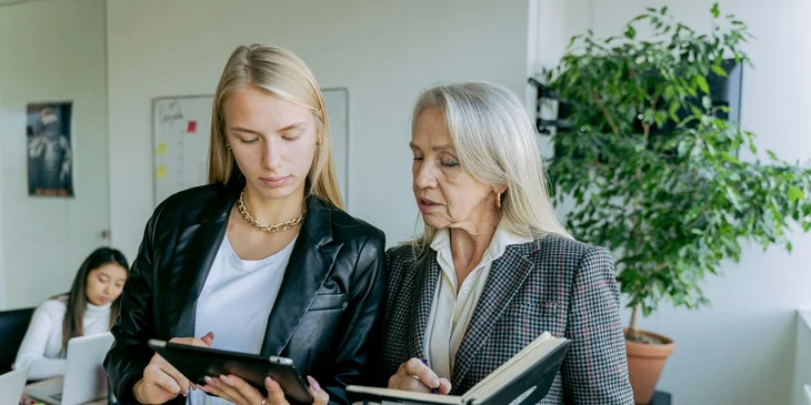 A part-time and full-time employee discuss work in the office.