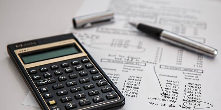Calculator, financial documents, and a pen on the desk of a payroll staff member.