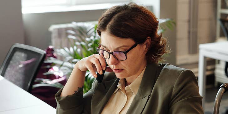 A payroll specialist working on a computer while talking on the phone.