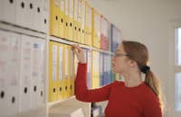 Uma mulher procurando um arquivo pessoal em uma prateleira.