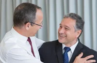 Zwei lächelnde Männer führen in einem Büro ein Gespräch.