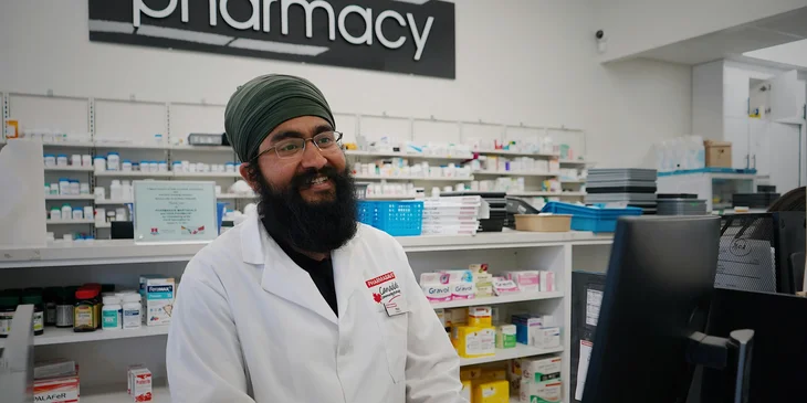 A pharmacist smiling in a pharmacy.