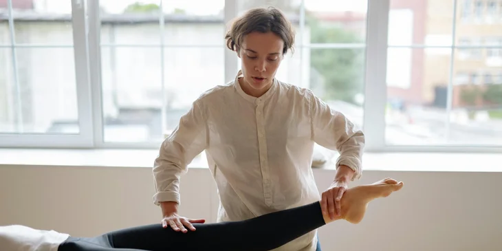 A physical therapist assistant helps the patient with muscle stretching.