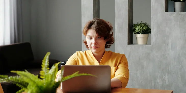 A woman working on a laptop at a table.