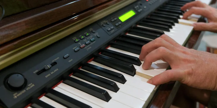 A piano teacher plays a piece on the piano.