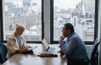 Dos personas en una junta de trabajo platicando sobre el plan de mejora del rendimiento.