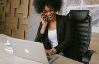 Una sonriente mujer atendiendo una llamada telefónica después de enviar un correo electrónico anunciando al nuevo integrante del personal.