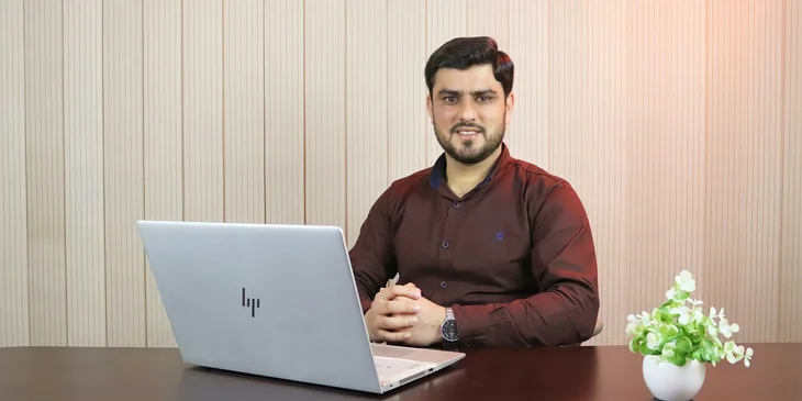A man in red sweater using a laptop.
