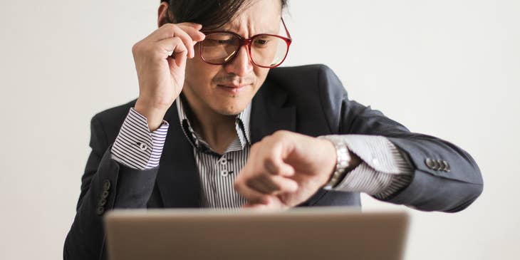 product manager behind laptop checking the time