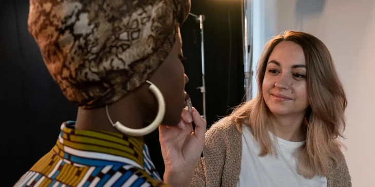 A beautician applying make-up to the model.