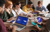 Un groupe de professionnels travaillant et se réunissant autour d'une table en bois avec des ordinateurs portables et des cahiers.