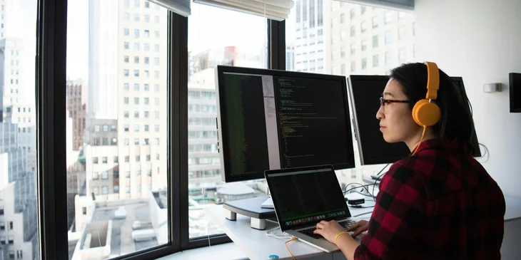 A Python developer gazing out the window while working at her desk.