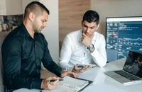 Dos personas hablando con gráficos y números sobre los beneficios complementarios de desempleo.