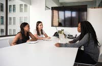 Mujeres sentadas en un escritorio blanco en una oficina de una empresa.