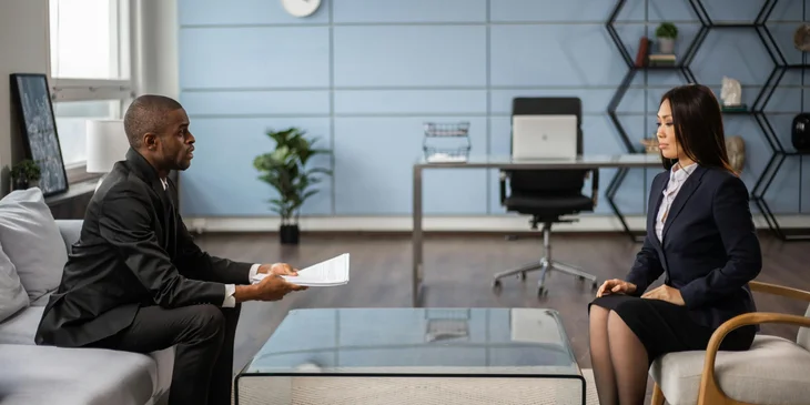 A man interviewing a woman in an office setting.