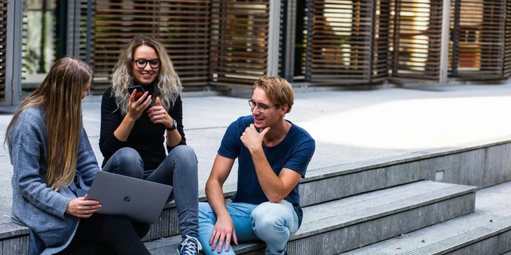 Three people sitting on the stairs, engaged in conversation.