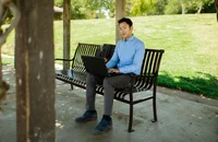 Un homme travaillant sur son ordinateur portable à l’extérieur.