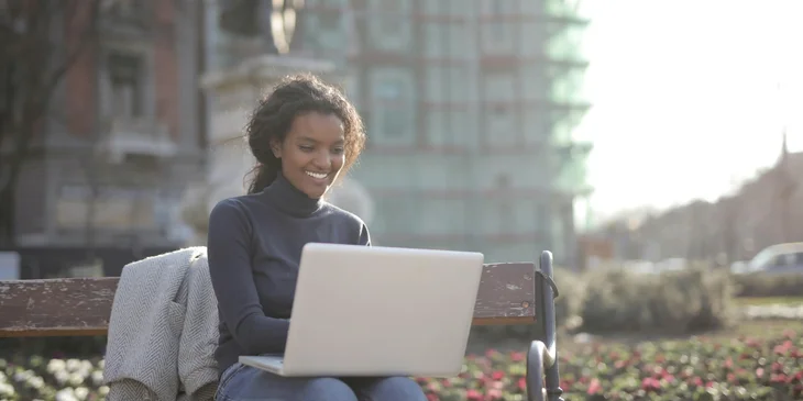 Una mujer sonriendo mientras escribe en una laptop.
