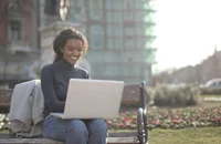Una mujer sonriendo mientras escribe en una laptop.
