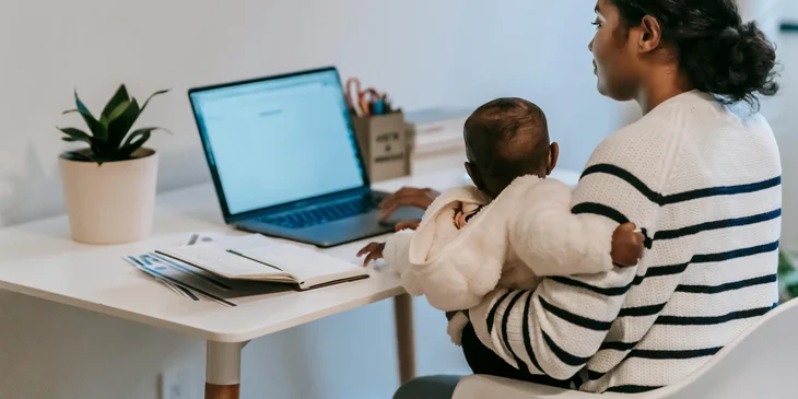 An employee reviewing the company's remote work policy while holding her child.