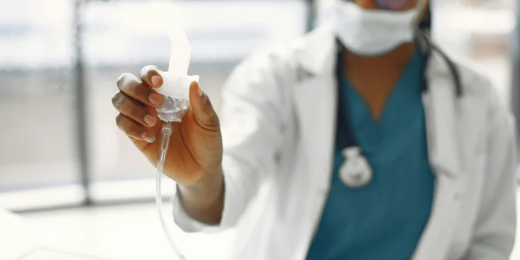 A respiratory therapist administers medication to the patient.