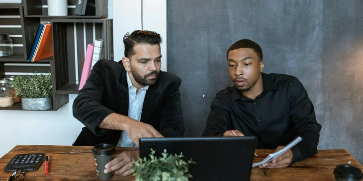 Two colleagues working on a laptop and discussing work.