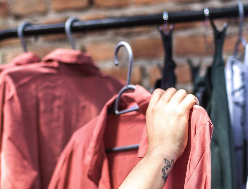 Person holding a red shirt on a hanger in a retail store.