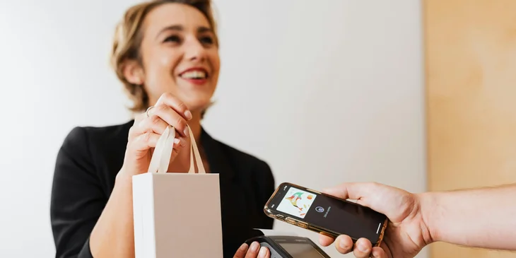 A cashier hands over the purchased item after the client has made the payment.
