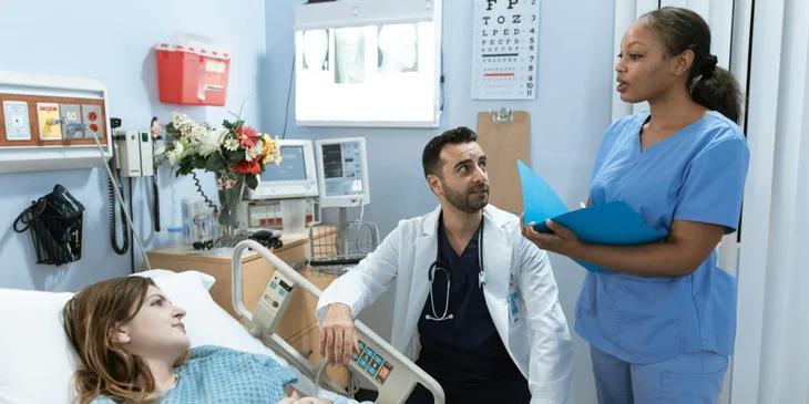 A nurse updating the patient along with the doctor.