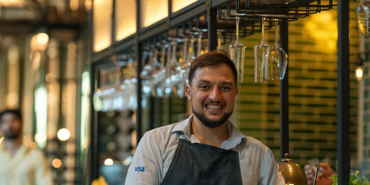 Ein lächelnder Kellner lehnt sich an die Theke einer Hotelbar.
