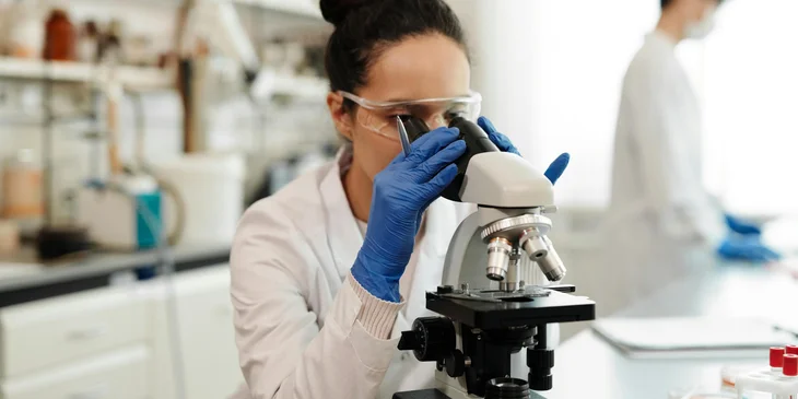 A scientist observing through a microscope.