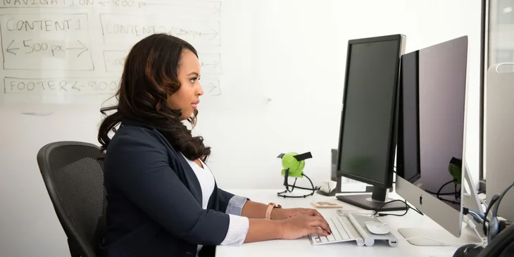 A woman wearing black suit jacket and using a computer.