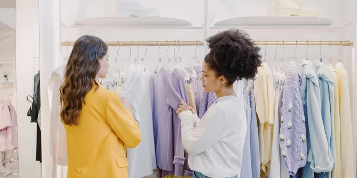 A sales assistant helping a client with clothing.