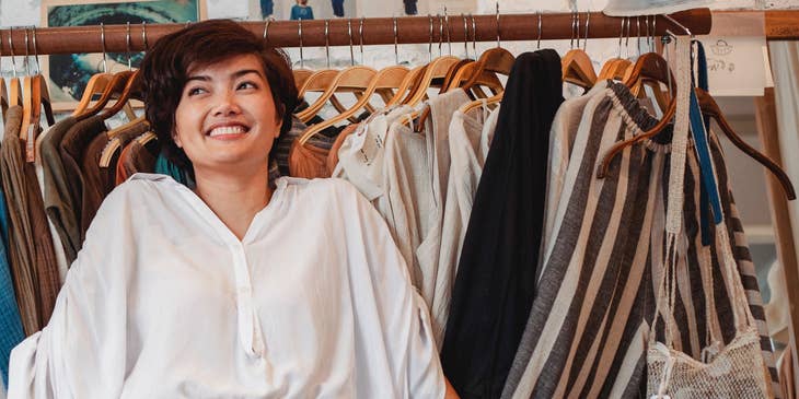 A sales associate standing by a rack of clothes.