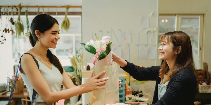 A sales associate hands over the flowers to a customer who placed the order.