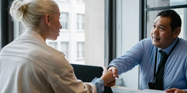A man and a woman shaking hands to finalize a deal.